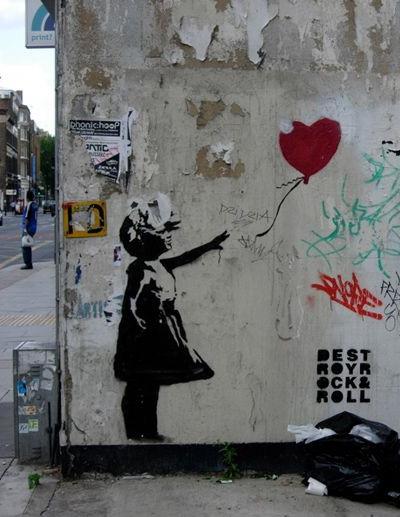the original “Girl with a Balloon” painted (graffitied) of the side of a dirty wall in the neighborhood of Bristol England